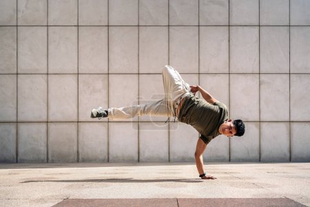 Foto de Cool joven latino haciendo movimientos de break dance en la calle y mostrando su talento. Él está mirando a la cámara. - Imagen libre de derechos