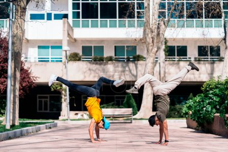 Foto de Dos amigos multiétnicos bailando en el parque y haciendo movimientos de break dance. - Imagen libre de derechos