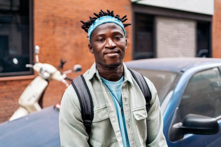 Téléchargez les photos : Jeune et confiant homme africain debout dans la rue et regardant la caméra. - en image libre de droit