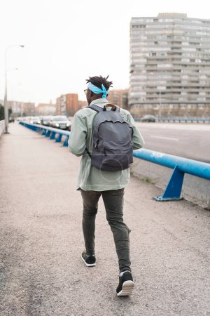 Téléchargez les photos : Homme africain non reconnu portant un sac à dos marchant dans la rue. - en image libre de droit