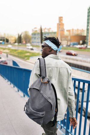Téléchargez les photos : Homme africain non reconnu portant un sac à dos marchant dans la rue. - en image libre de droit