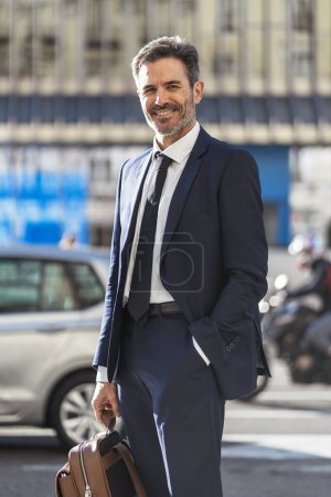 Photo for Portrait of male entrepreneur wearing classy suit standing with backpack in city and looking at camera - Royalty Free Image