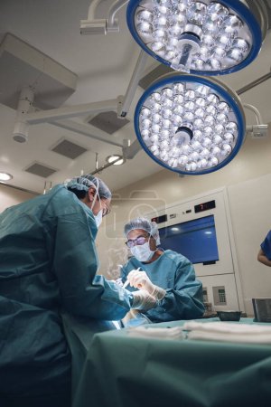 Foto de Concentrated surgeons engaging in rescue of male patient in operating room at hospital, Surgery, medical technology, health care and disease treatment concept - Imagen libre de derechos