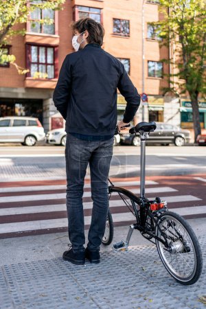 Téléchargez les photos : Stock photo of unrecognized man waiting in a zebra crossing with his detachable bike. - en image libre de droit