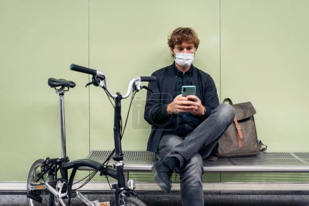 Téléchargez les photos : Photo du jeune homme assis dans le métro à côté de son vélo amovible. - en image libre de droit
