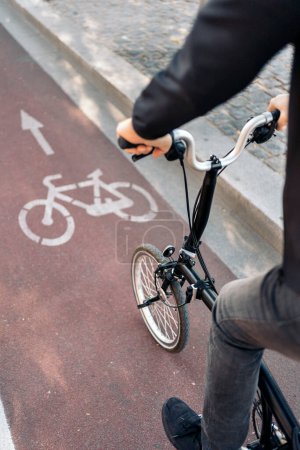 Téléchargez les photos : Photo de stock de l'homme méconnu chevauchant son vélo suivant piste cyclable. - en image libre de droit
