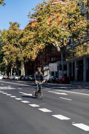 Téléchargez les photos : Photo de stock de bel homme utilisant son vélo détachable dans la rue pendant la journée ensoleillée. - en image libre de droit
