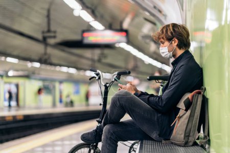 Téléchargez les photos : Photo du jeune homme assis dans le métro à côté de son vélo amovible. - en image libre de droit