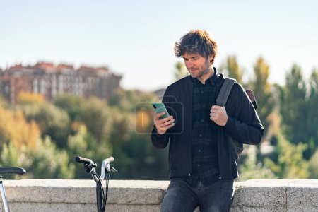 Téléchargez les photos : Photo d'un bel homme utilisant son téléphone portable dans la rue. - en image libre de droit