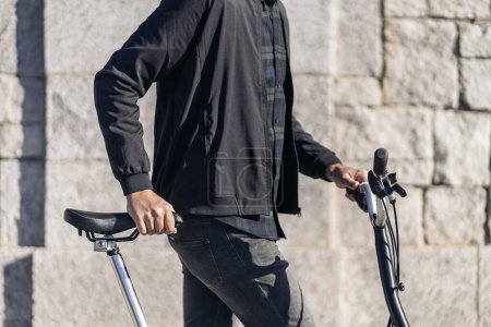 Photo for Stock photo of faceless man walking next to his removable bike in the street. - Royalty Free Image