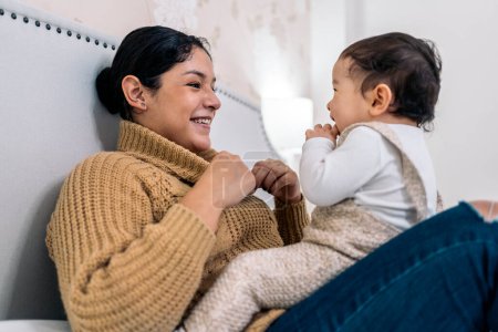 Téléchargez les photos : Photo de stock de jeune mère partageant un moment mignon avec son petit bébé dans la chambre. - en image libre de droit