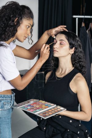 Téléchargez les photos : Stock photo of concentrated make up artist using eye shadow for her clients look - en image libre de droit