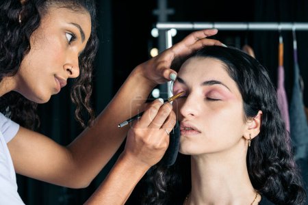 Téléchargez les photos : Photo de stock de belle jeune femme faisant du maquillage à son client en studio. - en image libre de droit