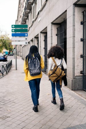 Téléchargez les photos : Photo de stock de filles afro non reconnues marchant dans la ville. - en image libre de droit