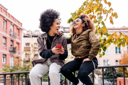 Photo for Stock photo of cool afro girls smiling and using phone in the street. - Royalty Free Image