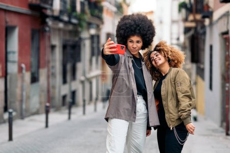 Foto de Foto de stock de hermosos amigos afroamericanos tomando fotos con el teléfono en la calle. - Imagen libre de derechos