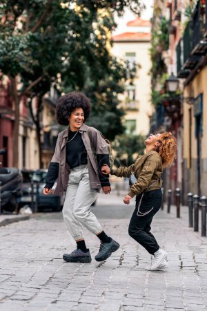Téléchargez les photos : Stock photo of casual happy afro girls laughing and walking in the city. - en image libre de droit