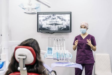 Téléchargez les photos : Photo de stock de dentiste montrant sa jeune patiente une radiographie. - en image libre de droit