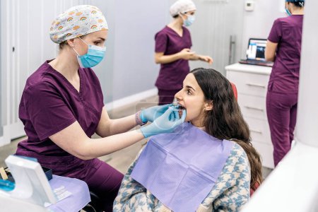 Téléchargez les photos : Stock photo de la femme assise dans la chaise du dentiste portant des couvertures de dents. - en image libre de droit