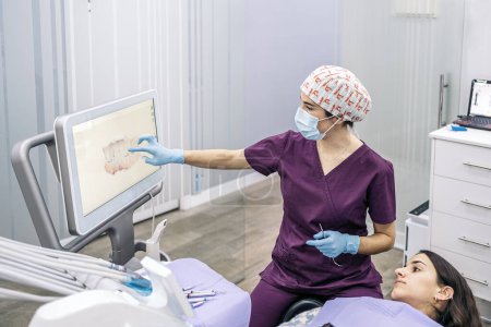 Téléchargez les photos : Photo d'une travailleuse d'une clinique dentaire montrant une radiographie à un patient. - en image libre de droit
