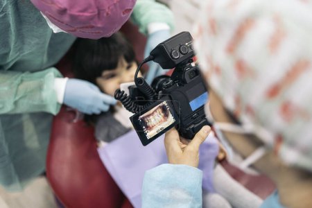 Photo for Stock photo of female dentist wearing face mask taking picture of a young patient. - Royalty Free Image