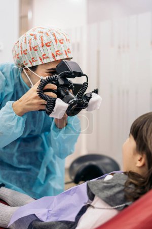 Foto de Stock photo of female dentist wearing face mask taking picture of a young patient. - Imagen libre de derechos