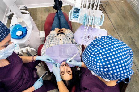 Téléchargez les photos : Stock photo of female dentists wearing protective face mask examining a patient. - en image libre de droit