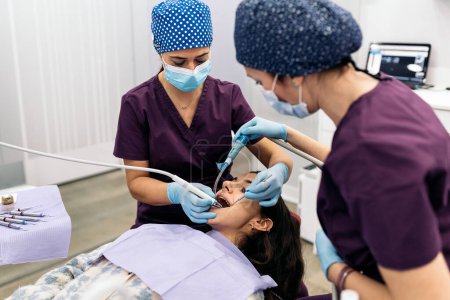 Téléchargez les photos : Photo de stock de femmes dentistes portant un masque protecteur examinant un patient. - en image libre de droit