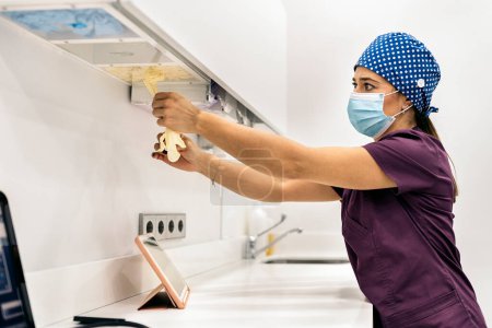 Photo for Stock photo of woman wearing face mask and hair net working in modern dental clinic. - Royalty Free Image