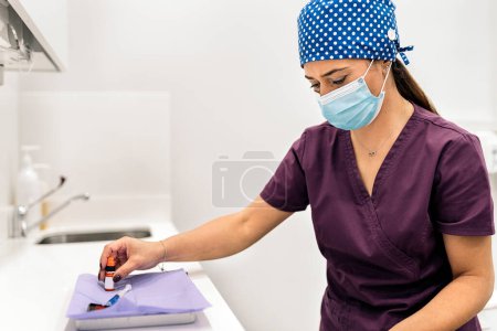 Foto de Foto de stock de la mujer que usa mascarilla y red para el cabello trabajando en la clínica dental moderna. - Imagen libre de derechos