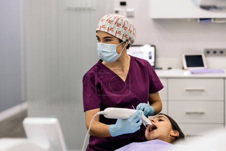 Foto de Foto de stock de dentista femenina con mascarilla protectora examinando a un paciente. - Imagen libre de derechos