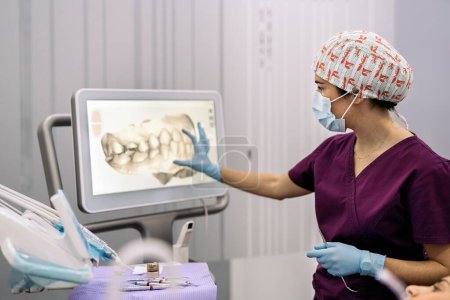 Foto de Foto de stock de trabajadora de clínica dental que muestra una radiografía a un paciente. - Imagen libre de derechos