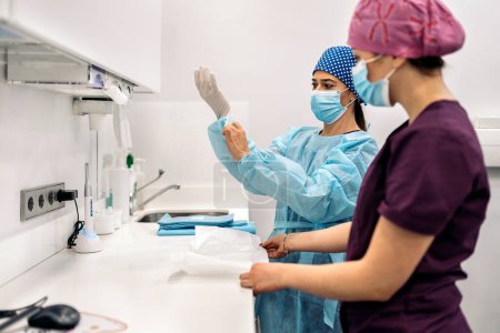Téléchargez les photos : Stock photo of women wearing face mask and hair net working in modern dental clinic. - en image libre de droit
