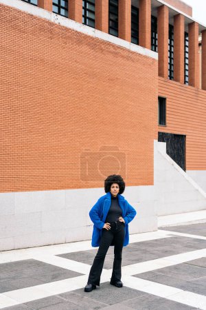 Téléchargez les photos : Photo de stock de jeune femme afro avec regard expressif regardant la caméra. - en image libre de droit