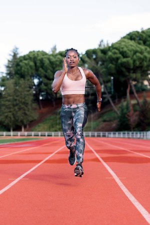 Foto de Foto en stock de una vista frontal de un velocista afroamericano corriendo en una pista de atletismo - Imagen libre de derechos