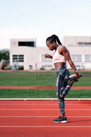 Photo for Stock photo of an African-American sprinter stretching her legs before training - Royalty Free Image