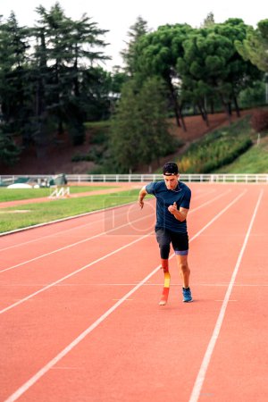 Téléchargez les photos : Photo de stock de jeune athlète s'entraînant avec une prothèse de jambe en piste de course. - en image libre de droit