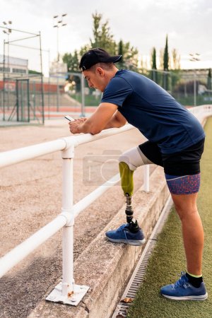 Photo for Disabled man athlete using his phone while doing a break. - Royalty Free Image
