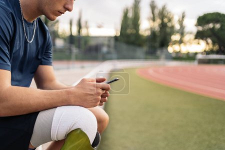 Photo for Disabled man athlete using his phone while doing a break. - Royalty Free Image