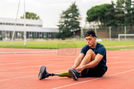 Photo for Stock photo of disabled man athlete taking a break and tying his trainers. Paralympic Sport Concept. - Royalty Free Image