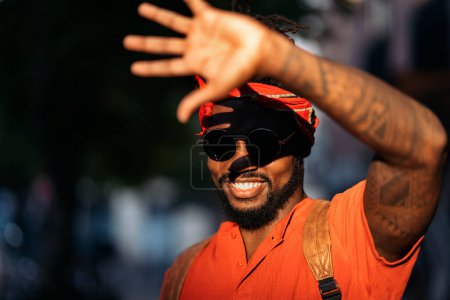 Foto de Foto en stock del atractivo joven afroamericano con su mano levantada cubriendo el sol. - Imagen libre de derechos