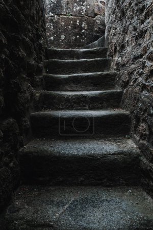 Téléchargez les photos : Un mystérieux escalier enroulant un mur sombre, illuminé par les ombres des structures construites. Il faut explorer la voie à suivre. Orientation portrait avec espace de copie - en image libre de droit