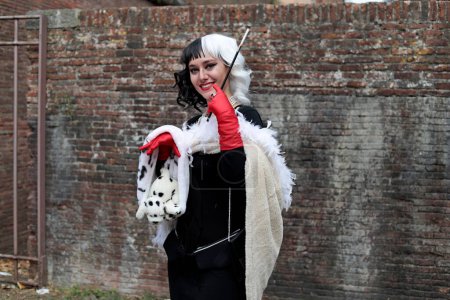 Foto de Lucca, Toscana, Italia - 1 de noviembre de 2022: Cosplayer disfrazado de Cruella de Vil, personaje de la novela y película de animación Cien y un dálmatas en los cómics y juegos de Lucca 2022 - Imagen libre de derechos