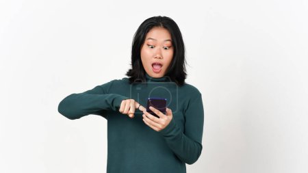 Téléchargez les photos : Tenant Smartphone choqué visage et en utilisant smartphone de belle asiatique femme isolé sur fond blanc - en image libre de droit