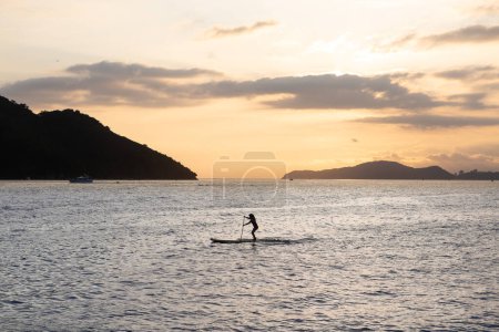 Photo for Girl practicing stand up paddle during the late afternoon in Santos bay. - Royalty Free Image
