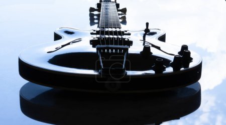Foto de Guitarra semi-acústica colocada sobre una mesa de mármol blanco que refleja el cielo - Imagen libre de derechos