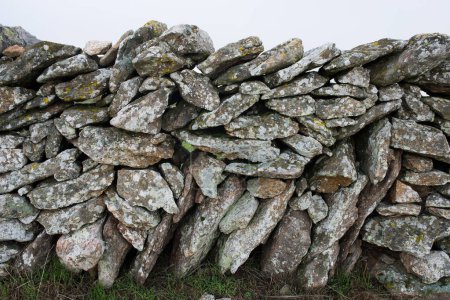 Traditional stone fence in the countryside. Piled stones.