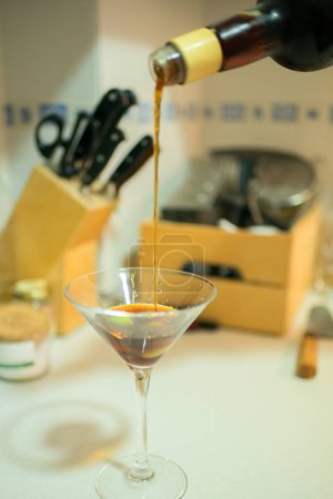 Photo for Pouring a martini glass in a domestic kitchen. Glass cup - Royalty Free Image