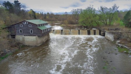 Téléchargez les photos : Ancien moulin à eau près d'une cascade au printemps sur une belle rivière au Québec, Canada - en image libre de droit