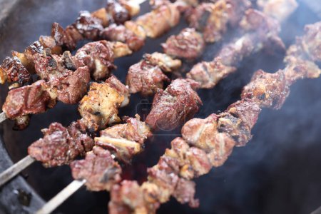 Photo for Preparation of shish kebab bbq. Close-up shot of meat skewers in barbecue picnic on open fire. - Royalty Free Image